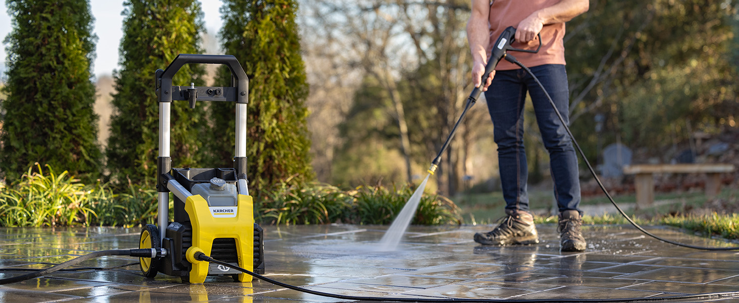 A person cleaning a stone patio using a pressure washer