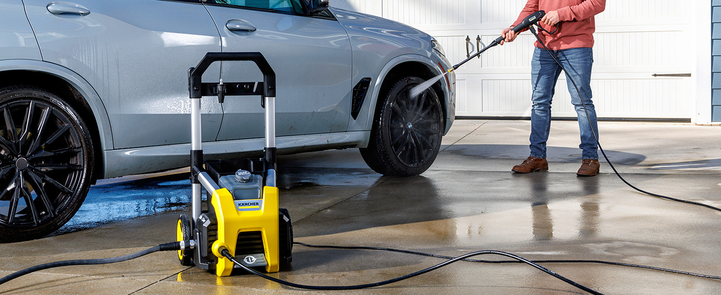 A person cleaning a car using a pressure washer